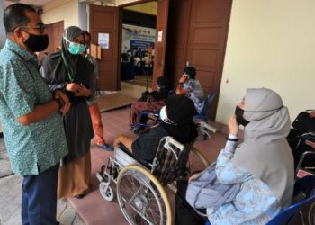 MOHAMED Khaled Nordin (kiri) beramah mesra dengan warga emas yang sedang menunggu giliran untuk diberi vaksin ketika menyampaikan sumbangan Yayasan Pasir Gudang kepada PPV di Dewanraya Bandar Seri Alam, Pasir Gudang, Johor. - FOTO/RAJA JAAFAR ALI