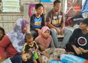 AKIDI Hamid (duduk, kanan) bertanya khabar keluarga Mohamad Amirul Aiman bersama isteri dan lima anak mereka ketika menghantar sumbangan di Kampung Tok Derpah, Alor Pasir, Rantau Panjang, Kelantan. – FOTO/ROHANA ISMAIL