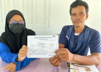 NOR Asmira Mohd. Nasir (kiri) bersama bapanya menunjukkan surat rawatan penyakitnya di Kampung Padang Licin, Rantau Panjang, Kelantan- MINGGUAN/YATIMIN ABDULLAH