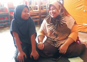 NORAZLINDA Deraman bersama anak tunggalnya, Nor Amalina Mohd. Faizal berkongsi cerita selepas terpaksa meredah banjir untuk berpindah ke PPS SK Alor Pasir, Tanah Merah, Kelantan. – FOTO/ROSMIZAN RESDI