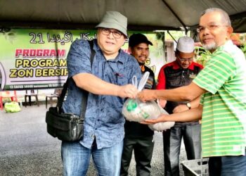 ROSNAZLI Amin (kiri) menyerahkan baja organik kepada penduduk pangsapuri di Kubang Kerian, Kota Bharu, Kelantan. - FOTO/ROSLIZA MOHAMED