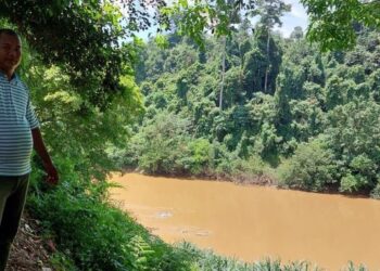 HARUN Ismail menunjukkan Sungai Lebir yang didakwa tercemar sehingga menjejaskan spesies ikan di Kampung Pasir Linggi, Pos Lebir, Gua Musang, Kelantan. – FOTO/AIMUNI TUAN LAH