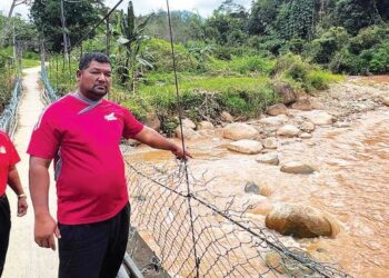 RIAN Bujang (kanan) menunjukkan air keruh di Sungai Belatop di Kampung Brooke Lama, Gua Musang, Kelantan. – FOTO/AIMUNI TUAN LAH