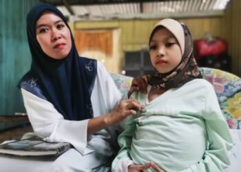 SITI Nazirah Razali (kiri) menunjukkan keadaan Nur Ariana Mohd. Shahrul Afendi yang mengidap kanser perut sejak tiga tahun lalu di Kampung Pauh Belukar, Badang, Pengkalan Chepa, Kota Bharu, Kelantan, semalam. - FOTO/ROSALWANI CHE SOH