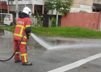 ANGGOTA bomba membersihkannya kawasan tumpahan minyak diesel di Kampung Gok Kapur, Kota Bharu, Kelantan. - FOTO/IHSAN BOMBA