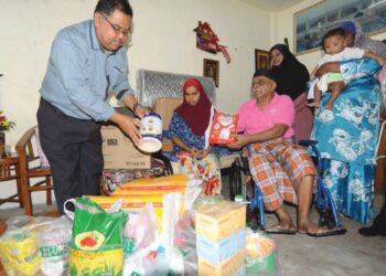 MAS IMRAN ADAM (kiri) menyampaikan sumbangan keperluan asas serta peralatan elektrik kepada Abd. Hameed Uthman (berkerusi roda) yang menghidap sakit saraf dan anaknya Hathijah Beevi di rumah mereka di Taman Cendana, Pasir Gudang, Johor,