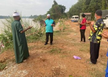AHLI Dewan Undangan Negeri (ADUN) Chenor, Mujibur Rahman Ishak (dua dari kiri) berdoa ketika meninjau operasi mencari dan menyelamat mangsa lemas di Sungai Pahang di Bera, Pahang.