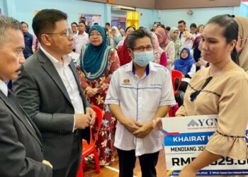 LUSIMOI Matsasak (kanan) menerima sumbangan khairat kematian YGMB daripada Raisin Saidin, sambil disaksikan oleh Wan Munadi Wan Mamat (dua, kiri) di Dewan SK Malawa, Sepanggar, hari ini.