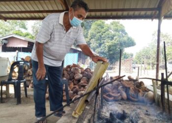 BUDZI Hisab membakar lemang di gerai Lemang Panas Mak Indok, Kampung Durian Daun, Melaka. - UTUSAN/MUHAMMAD SHAHIZAM TAZALI