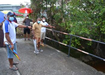 BEBERAPA orang penduduk menunjukkan longkang yang tidak diselenggara dengan baik sehingga menjadi punca kepada kejadian banjir ketika ditemui di Taman Mok Sum, Rasah, Seremban kelmarin. - FOTO/ZAKKINA WATI AHMAD TARMIZI