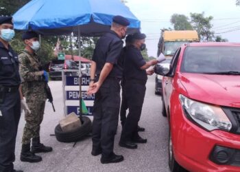 OSMAN Mamat (kanan) memeriksa dokumen perjalanan pemilik kenderaan ketika meninjau SJR  Jalan Ayer Putih  di Taiping hari ini. - UTUSAN/WAT KAMAL ABAS