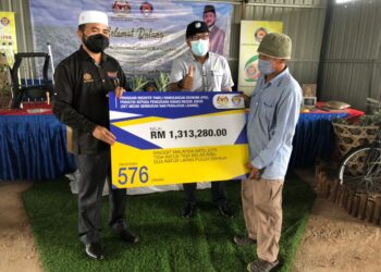 NIK Muhammad Zawawi Salleh (kiri) menyerahkan replika bantuan kepada pengusaha nanas ketika melakukan lawatan ke Projek Kelompok Tanaman Nanas Parit Ghani, Simpang Renggam di Kluang, Johor.