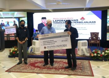 TENGKU Mohamad Rizam Tengku Abdul Rahman (tengah) menyampaikan replika cek kepada Pengarah Kesihatan Kelantan, Datuk Dr Zaini Hussin untuk disalurkan kepada Pusat Pemberian Vaksin (PPV) di Kompleks Islam Jubli Perak, Panji Kota Bharu, Kelantan, hari ini.