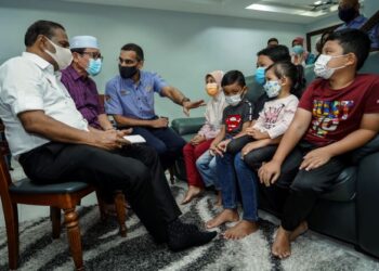 M. Saravanan (kiri) bersama Ketua Eksekutif Pertubuhan Keselamatan Sosial (Perkeso), Datuk Seri Dr. Mohammed Azman Aziz Mohammed (tiga dari kiri) menyantuni lima beradik yang menjadi yatim piatu selepas kehilangan ibu bapa mereka akibat jangkitan Covid-19 di Seri Kembangan, Selangor, hari ini. -UTUSAN/FARIZ RUSADIO 