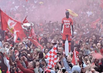LAUTAN merah penyokong Liverpool yang meraikan kepulangan pasukan itu di sekitar bandar Liverpool mengangkat replika Sadio Mane bulan lalu. – AFP