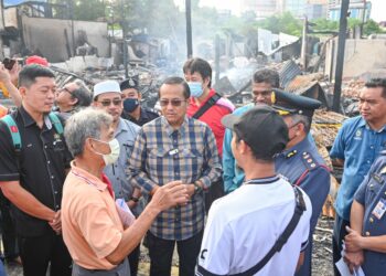 AHMAD Samsuri Mokhtar (tengah) bertanyakan sesuatu kepada pemilik rumah kedai yang terbakar ketika melawat tapak kebakaran di Kampung  Cina, Kuala Terengganu, hari ini. - UTUSAN/PUQTRA HAIRRY ROSLI