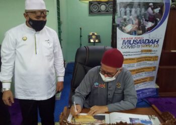 ZULKIFLI Mohamad Al-Bakri  menandatangani buku lawatan semasa menghadiri Program Musa’adah 3.0 di Surau Al-Faizin, Taman Serai Permai di Bagan Serai, Perak, hari ini. - UTUSAN/WAT KAMAL ABAS