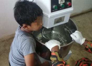 ANGGOTA bomba membantu kanak-kanak yang tersepit tangan kirinya pada mesin penguli tepung dalam kejadian di Bukit Gantang, Perak, hari ini. - IHSAN JBPM