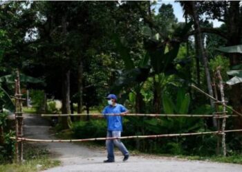 SEORANG penduduk Kampung Dusun Pak Senam memasang pagar daripada buluh bagi menghalang orang luar membawa Covid-19 ke lokaliti itu. – FOTO MEDIA SOSIAL