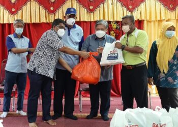 SYED AZMI Syed Nazir Ahmad (empat dari kanan) menyerahkan barangan makanan kepada mangsa banjir di SRA JAIM Kampung Morten, Melaka. - UTUSAN/AMRAN MULUP
