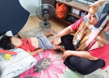 NUR UMI ADILAH Adlan melihat Muhd. Khalis Amsyar Ikhwan yang terlantar menunggu pembedahan di Kampung Belimbing Dalam, Durian Tunggal, Melaka. - FOTO/AMRAN MULUP