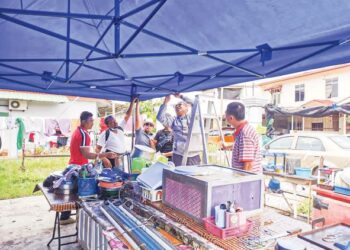 ANGGOTA PSBM memasang khemah baru sambil dibantu Nizam Tamby (dua dari kiri) di tapak gerainya di Taman Limbongan Permai, Melaka. - UTUSAN/DIYANATUL ATIQAH ZAKARYA