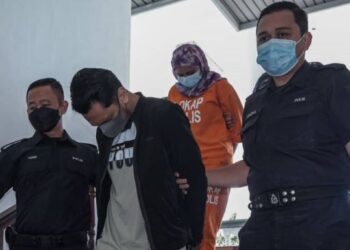 KEDUA tertuduh diiring keluar anggota polis selepas mengaku tidak bersalah di Mahkamah Majistret, Ayer Keroh, Melaka atas pertuduhan mencuri barang kemas keluarga pesakitnya bernilai RM12,000. - FOTO/SYAFEEQ AHMAD