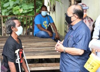 HENRY Sum Agong (kanan) menyantuni penerima vaksin, Hadi Degil di rumahnya di Kampung Orang Asli Bukit Payung, Alor Gajah, Melaka. - UTUSAN/MUHAMMAD SHAHIZAM TAZALI