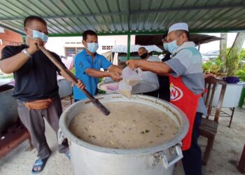 BAHAROM Sulaiman (kiri) sedang mengacau bubur lambuk sambil dibantu para sukarelawan lain untuk diagihkan kepada orang ramai di Kampung Bukit Piatu, Melaka. - UTUSAN/MUHAMMAD SHAHIZAM TAZALI
