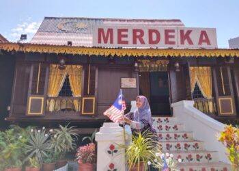 AMINAH Abu Bakar meletakkan Jalur Gemilang di hadapan rumahnya di Kampung Morten, Melaka sempena bulan kemerdekaan. - UTUSAN/MUHAMMAD SHAHIZAM TAZALI