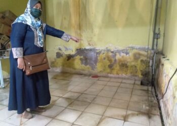 SEORANG peniaga, Harlikah Rasmijan menunjukkan lubang tersumbat yang menyebabkan Bazar Kraftangan di Dataran Pahalawan dinaiki air kumbahan. - UTUSAN/MUHAMMAD SHAHIZAM TAZALI