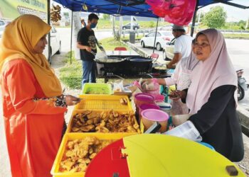 ROBIAH Yaacob (kanan) melayan pelanggan membeli pisang goreng di Jalan Tanjung Minyak Perdana, Melaka. - UTUSAN/AMRAN MULUP
