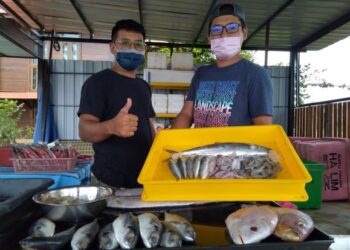 UNGKU Mohd. Hadi Ungku Mohd. Noor (kanan) bersama adiknya, Ungku Mohd. Hilmi menunjukkan set ikan tenggiri yang berharga RM35 di Gerai Ikan Pulau Gadong di Klebang Besar, Melaka. – UTUSAN/MUHAMMAD SHAHIZAM TAZALI