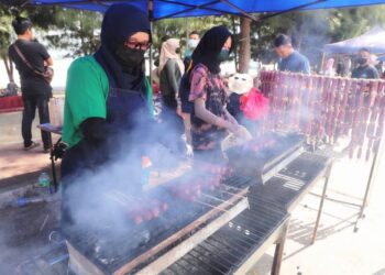 UMI KALSOM Ibrahim bersama anaknya, Nur Fazirah Abdullah, 17, (kanan) menyiapkan hidangan pelanggan iaitu tongmo yang dijual di Pantai Klebang, Melaka. - UTUSAN/RASUL AZLI SAMAD