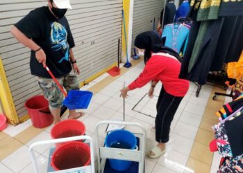 DUA peniaga membersihkan air kumbahan yang membanjiri tapak Bazar Kraftangan di Dataran Pahlawan di Banda Hilir, Melaka. - UTUSAN/MUHAMMAD SHAHIZAM TAZALI