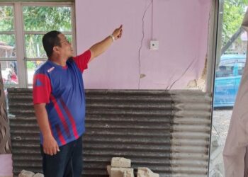 RAHMAT Adom menunjukkan keretakan dinding rumah Nazira Saidin kesan daripada rempuhan kereta Perodua Myvi yang terbabas di tepi jalan Serkam Pantai, Merlimau, Melaka, Isnin lalu. – FOTO/MUHAMMAD SHAHIZAM TAZALI