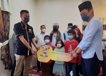 SULAIMAN Md. Ali (belakang) menyaksikan Mohd. Salleh Hamidon (kiri) menyerahkan replika kunci rumah CSR LPM kepada Muhammad Ikram Ibrahim (kanan) di Kampung Pekan Tangga Batu, Pantai Kundor, Melaka. – UTUSAN/AMRAN MULUP