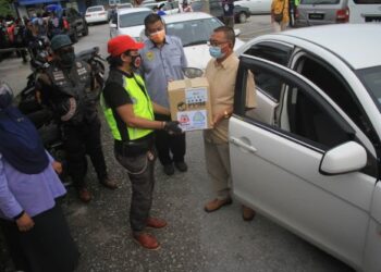 MOHD. Razmi Khalid menyerahkan kotak makanan kepada salah seorang pemandu limosin dan teksi LTAPP di Bayan Lepas, Pulau Pinang hari ini.