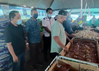 AHMAD NAZLAN Idris (depan) smelihat minyak masak paket antara barang keperluan dapur dijual sempena Program Jualan Keluarga Malaysia di Felda Sungai Retang di Jerantut, Pahang. - UTUSAN/HARIS FADILAH AHMAD