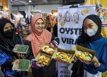PENGUNJUNG menunjukkan masakan tiram yang dibeli di Empayar Makanan MAHA 2022 di Serdang, Selangor, semalam.  – UTUSAN/MUHAMAD IQBAL ROSLI