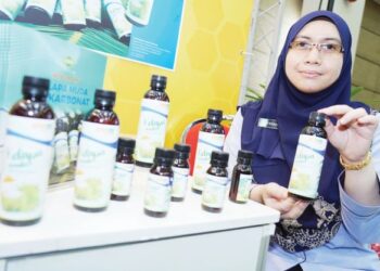 Nur Farah Hani Muhammad menunjukkan produk minuman air kelapa berkarbonat yang mampu bertahan lebih lama berbanding air kelapa segar. -UTUSAN/FAUZI BAHARUDIN.