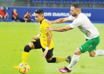 FAISAL Halim (kiri) cuba melepasi pertahanan Turkmenistan, Elman Tagayev dalam aksi persahabatan kelmarin. – UTUSAN/RAJA JAAFAR ALI