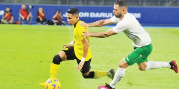 FAISAL Halim (kiri) cuba melepasi pertahanan Turkmenistan, Elman Tagayev dalam aksi persahabatan kelmarin. – UTUSAN/RAJA JAAFAR ALI