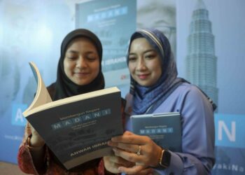 Penjawat awam, Wan Farah Wan Nasrudin (kanan) dan Nor Zarifah Saleh melihat buku Membangun Negara Madani di Pusat Konvensyen Antarabangsa Putrajaya (PICC), Putrajaya, baru-baru ini. – mingguan/FAISOL MUSTAFA