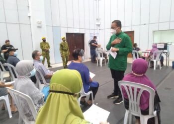 MOHD. Rafiq Naizamohideen (kanan) berbual dengan penerima vaksin di PPV Dewan Tun Ali, Bukit Katil, Melaka. - FOTO/MUHAMMAD SHAHIZAM TAZALI