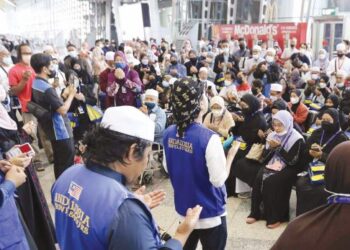 MUTAWIF bersama jemaah umrah membaca doa sebelum berangkat ke Tanah Suci pada penerbangan pertama umrah Andalusia Travel & Tours Sdn. Bhd. musim 2022/2023 (1444H) di KLIA, Sepang. – FOTO/FAISOL MUSTAFA