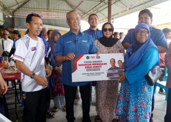 Muhyiddin Yassin menyampaikan sumbangan kepada seorang peniaga kedai runcit di Pagoh, Johor, baru-baru ini.