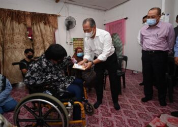 MUHYIDDIN Yassin menyampaikan bantuan kepada seorang penduduk dalam lawatannya ke  rumah pangsa di Tanjung Aru, Sabah, semalam. - GAMBAR FACEBOOK RASMI MUHYIDDIN YASSIN