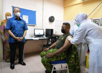 MUHYIDDIN Yassin menyaksikan seorang petugas barisan hadapan menerima suntikan vaksin Covid-19 semasa melawat Klinik Kesihatan Kampung Gial, Arau, Perlis, semalam. – UTUSAN/SHAHIR NOORDIN