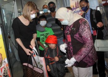 NANCY Syukri menyampaikan cenderahati kepada penumpang penerbangan Etihad EY0418 yang baru tiba selepas kerajaan Malaysia membuka semula sempadan di KLIA, Sepang, Selangor. - UTUSAN/ FAISOL MUSTAFA